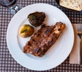 Grilled beef ribs served on plate with side dish of boiled potatoes and baked artichokes. Popular Spanish combination Royalty Free Stock Photo