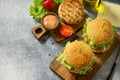 Delicious grilled burgers, hamburger sandwich with cutlet of chicken meat, melted cheese, tomatoes and bacon Royalty Free Stock Photo