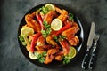 Delicious grilled chicken wings with lemon juice and chili pepper on black concrete background. Top view. Royalty Free Stock Photo