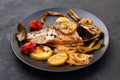 Delicious grilled dorado or sea bream fish with salad, spices, grilled dorada on a black plate. Top view, overhead, copy space Royalty Free Stock Photo