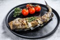 Delicious grilled hake with fresh thyme and tomatoes. Black background. Top view