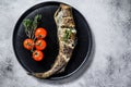 Delicious grilled hake with fresh thyme and tomatoes. Black background. Top view