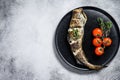 Delicious grilled hake with fresh thyme and tomatoes. Black background. Top view. Copy space