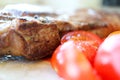Delicious grilled juicy pork meat steak with vegetables cherry tomatoes close up Royalty Free Stock Photo