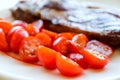 Delicious grilled juicy pork meat steak with vegetables cherry tomatoes close up Royalty Free Stock Photo