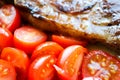 Delicious grilled juicy pork meat steak with vegetables cherry tomatoes close up Royalty Free Stock Photo