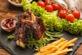 Delicious grilled ribs with vegetables, french fries and sauce on slate plate Royalty Free Stock Photo