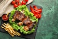 Delicious grilled ribs with vegetables, sauce and french fries on slate plate Royalty Free Stock Photo