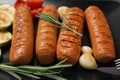 Delicious grilled sausages with rosemary on dark plate Royalty Free Stock Photo