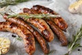 Delicious grilled sausages with rosemary and garlic on parchment Royalty Free Stock Photo