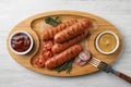 Delicious grilled sausages sauces on wooden tray, top view. Barbecue food