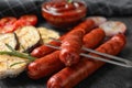 Delicious grilled sausages and vegetables on black table. Barbecue food Royalty Free Stock Photo