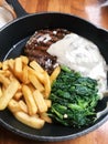 delicious grilled steak with french fries and green spinach with mushroom sauce served in hot pan