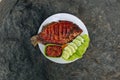 Delicious grilled tilapia nila bakar from indonesia with rice, tempeh, vegetables, and chilli sauce in plate