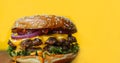 Delicious hamburger with cheese, lettuce, tomato, onion, ketchup, and mustard on a yellow background. Close-up Royalty Free Stock Photo