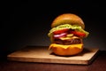 Hamburger with cheese, pickles, tomato, onions, lettuce on board Royalty Free Stock Photo