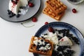 Delicious healthy breakfast. Belgian soft waffles with curd cheese cream and blueberry cherries lie white blue plate view from the Royalty Free Stock Photo