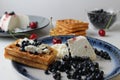 Delicious healthy breakfast. Belgian soft waffles with curd cheese cream and blueberry cherries lie white blue plate view from the Royalty Free Stock Photo