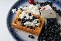 Delicious healthy breakfast. Belgian soft waffles with curd cheese cream and blueberry cherries lie white blue plate view from the Royalty Free Stock Photo