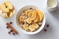 Delicious healthy breakfast. Oatmeal with banana, apple, nuts and cinnamon on a light gray background