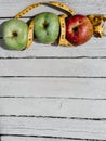 Delicious and healthy food is on the kitchen table. Three apples-yellow, green and red on a white wooden background and a yellow Royalty Free Stock Photo