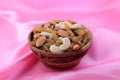 Delicious and healthy mixed dried fruit, nuts and seeds in a wooden bowl on pink silky background Royalty Free Stock Photo