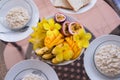 Delicious home breakfast served for three person. Oatmeals porrige and fruit bowl with mango, banana, passionfruit and Royalty Free Stock Photo