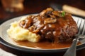 Delicious home cooked Salisbury steak with thick luscious brown mushroom gravy served with mashed potatoes on a plate