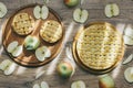 Delicious homemade apple pies and set of whole fresh green apples and cut apple and slices in soft natural light beaming. Royalty Free Stock Photo