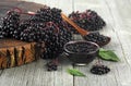 Delicious homemade black elderberry syrup in glass jar and bunches of black elderberry with green leaves on wooden desk Royalty Free Stock Photo
