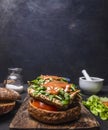 Delicious homemade burger with chicken in mustard sauce with arugula and herbs on a cutting board lettuce and spices border , Royalty Free Stock Photo