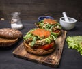 Delicious homemade burgers with chicken in mustard sauce with arugula and herbs on a cutting board lettuce and spices on woo