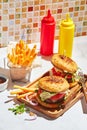 Delicious homemade burgers on wooden tray in bright sunlight. Burgers with veal cutlet, pamidor, cheese, red onion Royalty Free Stock Photo
