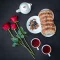 Delicious homemade Cake roll with tea-set, red roses on the black background, top view