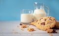 Delicious homemade chocolate chip cookies, paired with fresh milk in a glass and pitcher, placed on a white wooden floor and a Royalty Free Stock Photo