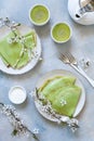 Delicious homemade green pancakes with blossoming cherry tree branches with green matcha tea on sky blue background. Top view, Royalty Free Stock Photo