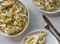 Classic pasta salad with mayonnaise, boiled eggs, corn, green peas, onions and sausage in a bowl on light background from above Royalty Free Stock Photo