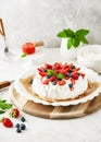 Delicious homemade Pavlova cake with fresh strawberries, blueberries, raspberries, whipped cream and strawberry sauce. Royalty Free Stock Photo