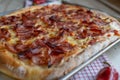 Thick crust pizza with salami, ham and cheese. Square shape on a baking sheet