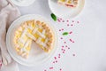 Delicious homemade puff pastry pie or cake with cream cheese filling and cherry on a white plate on a light stone background. Royalty Free Stock Photo