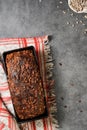 Delicious homemade rectangular wheat and rye bread with seeds, top view. Freshly baked bread lies in a baking dish on a gray table
