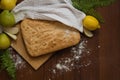 A delicious homemade simple pie lies on a wooden stand with a white tea towel next to lemons and pears on a dark wooden