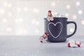 Delicious hot chocolate with marshmallow and litle snowmans on grey stone background. New Year bokeh