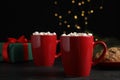 Delicious hot cocoa with marshmallows on black table against blurred lights, space for text Royalty Free Stock Photo
