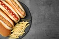 Delicious hot dogs and french fries on grey background, top view. Royalty Free Stock Photo