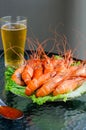 Delicious huge boiled king prawns, a glass of beer and hot sauce on a glass table