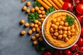 Delicious hummus topped with chickpeas, surrounded by fresh tomatoes and carrots, creating vibrant and healthy meal option