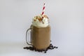 Delicious iced coffee or Frappuccino with whipped cream , syrup and a red straw . With Coffee beans isolated on white background