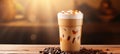 Delicious iced coffee in plastic cup with coffee seeds on mesmerizing bokeh background