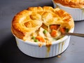 Delicious individual chicken creamy pot pie with vegetables in rich sauce with buttery flaky pastry. Cozy hearty meal for family